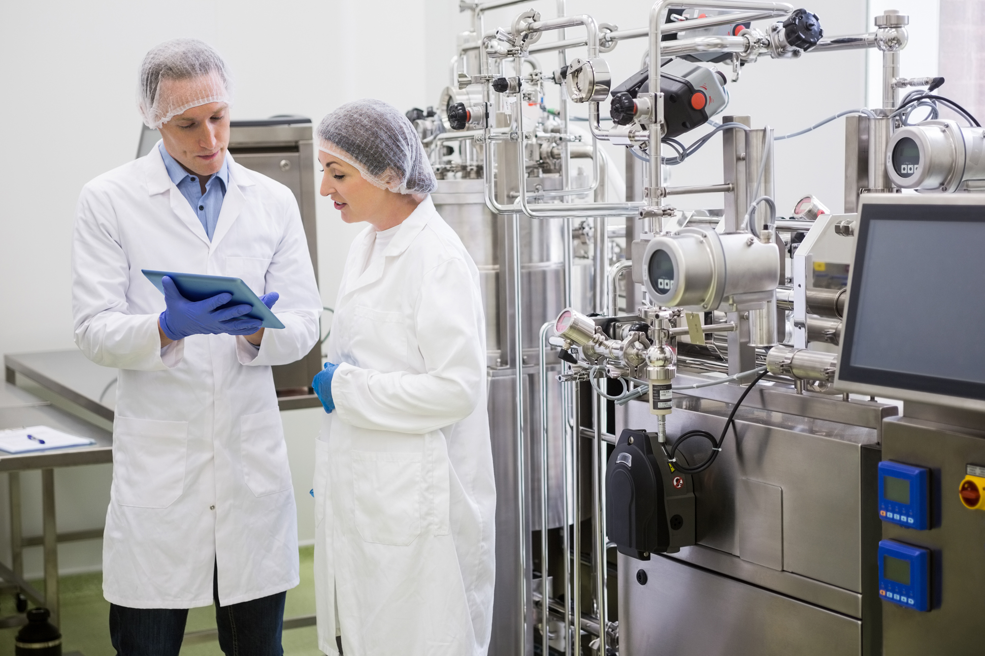 Food Safety Workers Looking at E-Reader Tablet in Manufacturing Plant