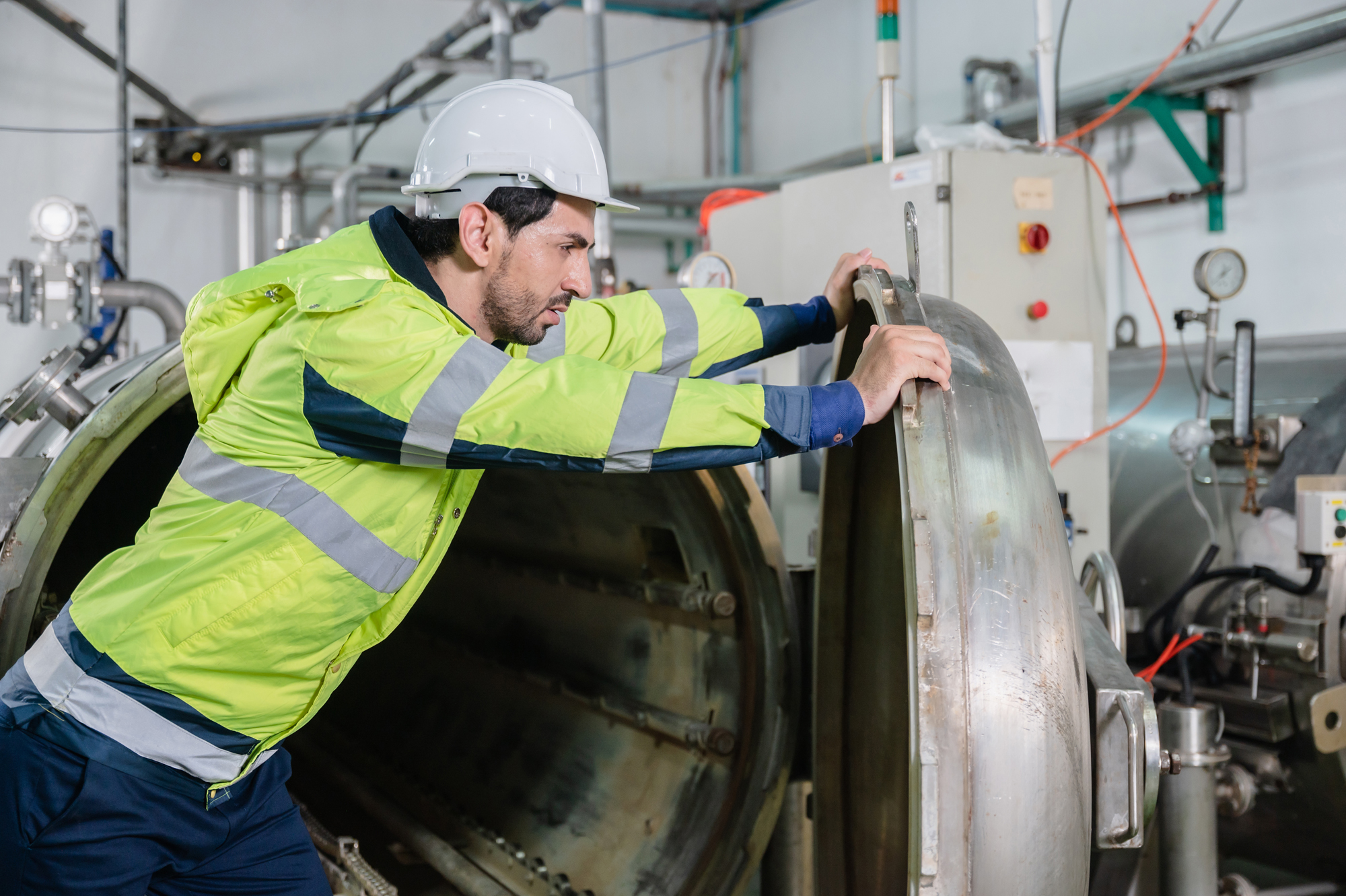 Male Worker with Yellow Safety Jacket Pushing Open Manufacturing Part