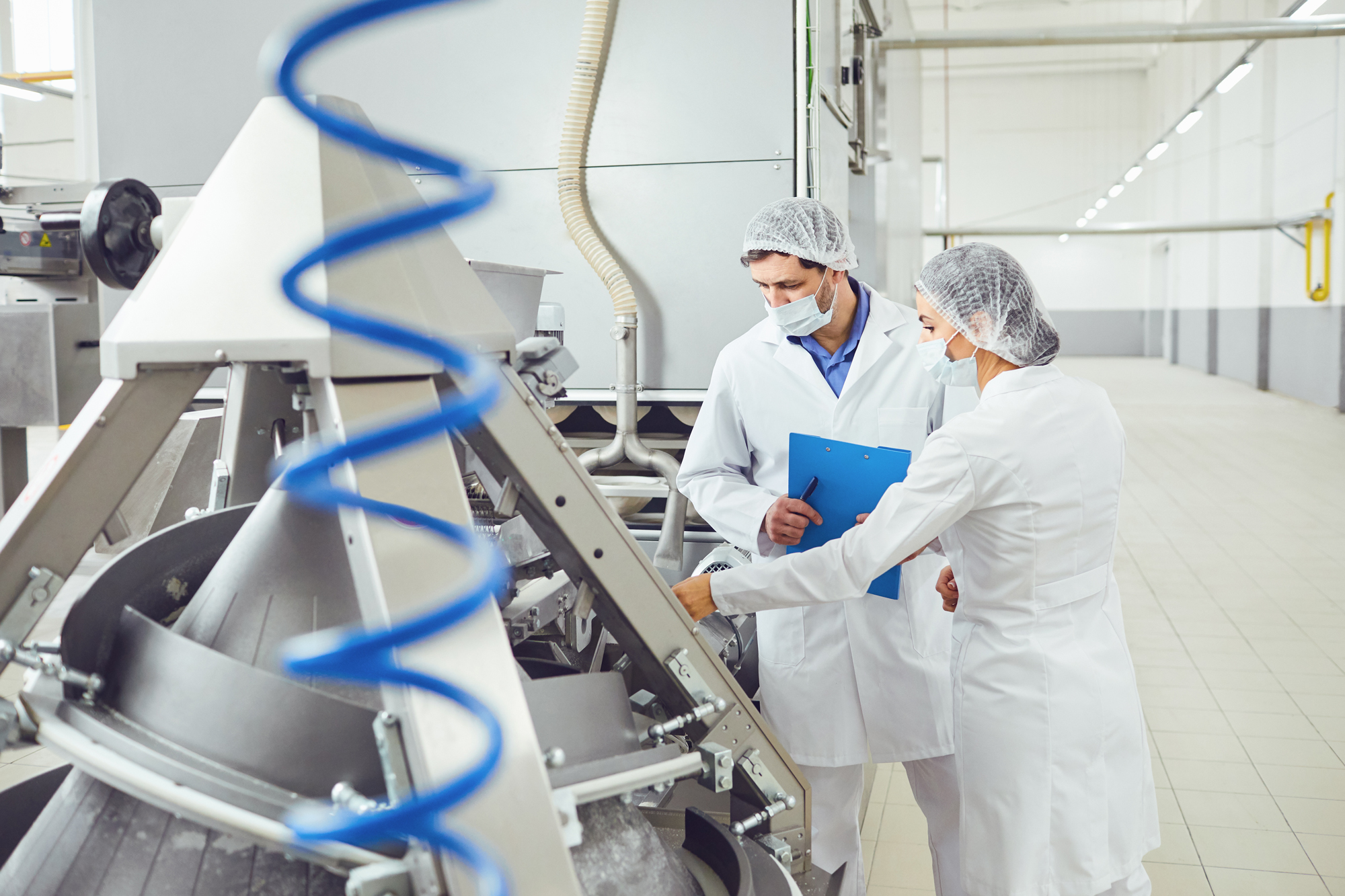 Female and Male Food Safety Workers Inspecting Production Area